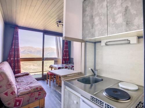 a kitchen with a sink and a couch and a window at travelski home classic - Résidence Vanguard in Le Corbier