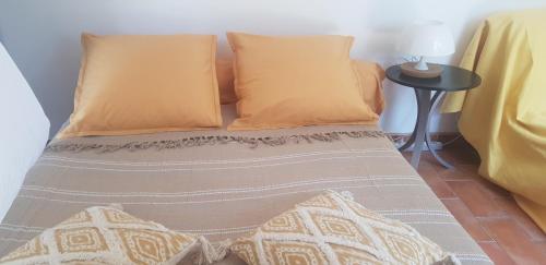 ein Bett mit zwei orangenen Kissen und einem Tisch in der Unterkunft Velodrome Maisonnette Studio 2 lits parking et piscine in Marseille