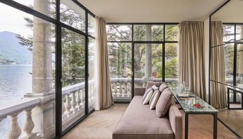 a living room with a couch and large windows at Villa Làrio Lake Como in Pognana Lario