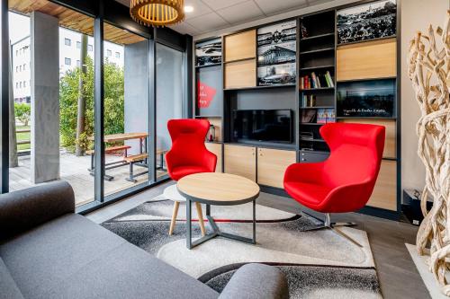 a living room with red chairs and a table at B&B HOTEL Bordeaux Est 3 étoiles in Tresses