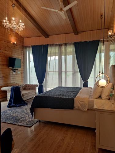 a bedroom with a large bed with blue curtains at The Brigadiers Cottage, Mussoorie in Mussoorie