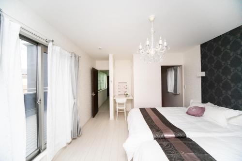 a bedroom with a large bed and a chandelier at Shiga Lakeside Villa in Imazu