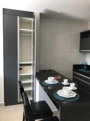 a kitchen with a table with plates and bowls on it at Flats Baia dos Porcos in Fernando de Noronha