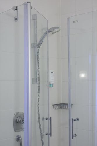 a shower with a glass door in a bathroom at Hotel Flora in Dormagen