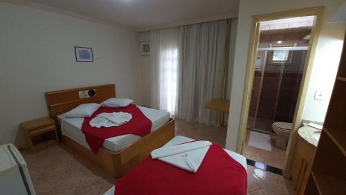 a hotel room with two beds and a bathroom at Hotel Pousada Ilha do Mar Bombinhas in Bombinhas