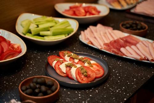 a table topped with plates of hot dogs and fruit at Hotel Glory in Oradea