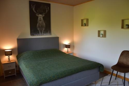 - une chambre avec un lit et une couette verte dans l'établissement Gîte du cheval blanc d'Houmont, à Sainte-Ode