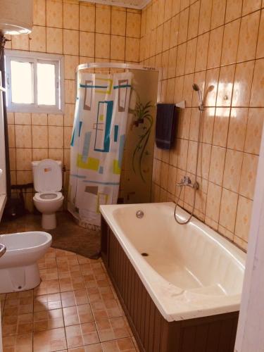 a bathroom with a tub and a toilet and a sink at Villa le Dakota in Yaoundé