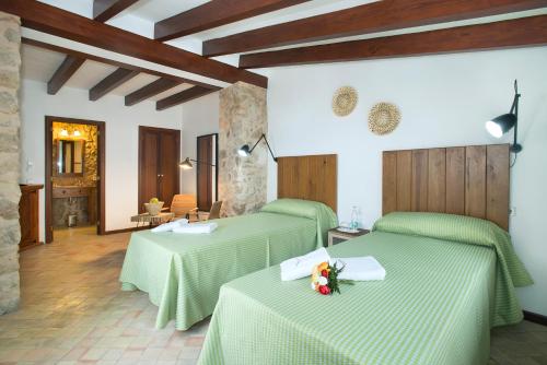 a room with two green beds with flowers on them at Petit Caimari - Turismo de interior in Caimari