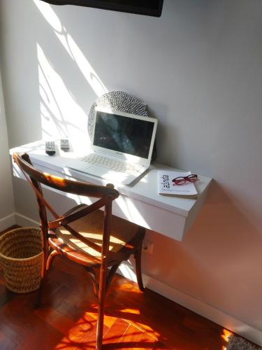 a laptop computer sitting on a white desk with a chair at Acacia Inn GuestHouse in Maputo