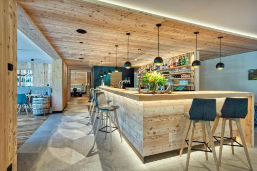a bar in a restaurant with wooden walls and stools at Brunelle Seiser Alm Lodge in Alpe di Siusi