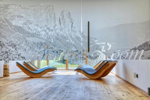 two chairs in a room with a mountain mural at Brunelle Seiser Alm Lodge in Alpe di Siusi