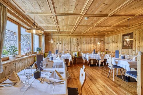 a restaurant with white tables and chairs and wooden walls at Brunelle Seiser Alm Lodge in Alpe di Siusi