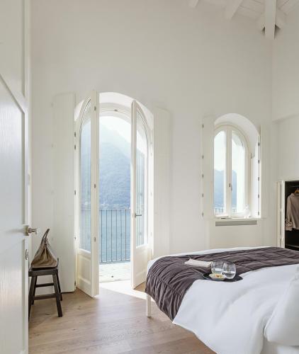 a white bedroom with a large bed and an open window at Villa Làrio Lake Como in Pognana Lario