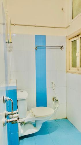 a bathroom with a white toilet and a blue floor at Half Moon Palace Chennai in Chennai