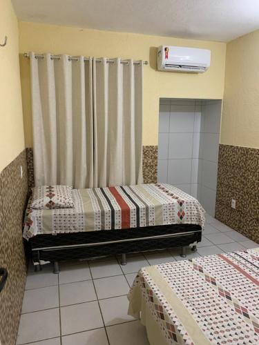 a room with two beds and a window with curtains at Flat Crystal Park Porto das Dunas- Cristal park in Aquiraz