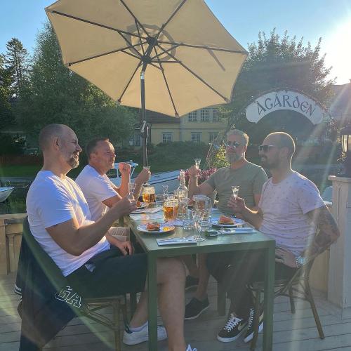 een groep mannen aan een tafel met drankjes bij Två Små Svin BnB in Trosa