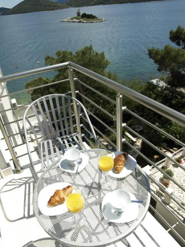 a table with cups and croissants on a balcony with the water at Apartments Tamaris in Klek