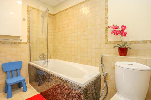 La salle de bains est pourvue d'une baignoire, de toilettes et d'un tabouret bleu. dans l'établissement JBR, 2-bedroom, next to beach, full marina view, à Dubaï