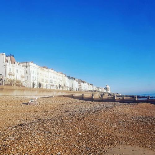 a row of buildings on a beach next to the ocean at Beautiful space on top of Edwardian house in Hastings