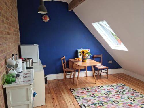 a kitchen with a table and a blue wall at Beautiful space on top of Edwardian house in Hastings