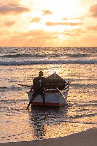 a man sitting on a boat on the beach at Morrumbene Beach Resort in Morrumbene