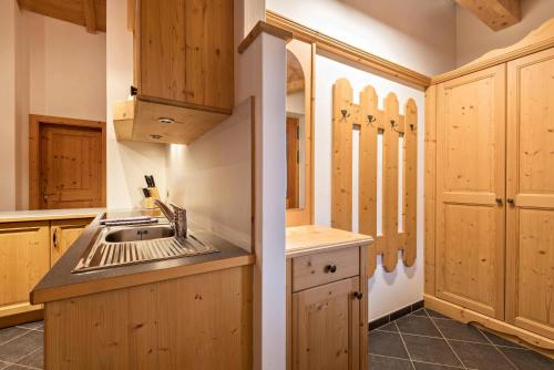 a kitchen with wooden cabinets and a sink at Aparthotel Monte 44 in Selva di Val Gardena