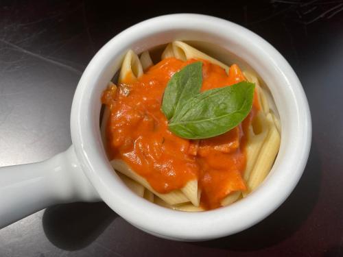 a bowl of pasta with tomato sauce and a basil leaf at Springhills Quito Airport in Tababela