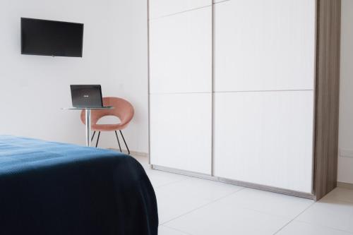 a bedroom with white wardrobes and a chair with a laptop at Malù B&B in Cimitile
