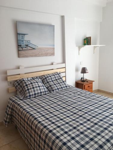 a bedroom with a bed with a checkered blanket at Berlin Lovely in Gran Tarajal