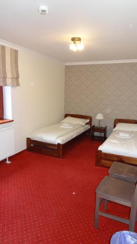 a room with two beds and a red carpet at Dworek Szwajcaria in Zwardoń