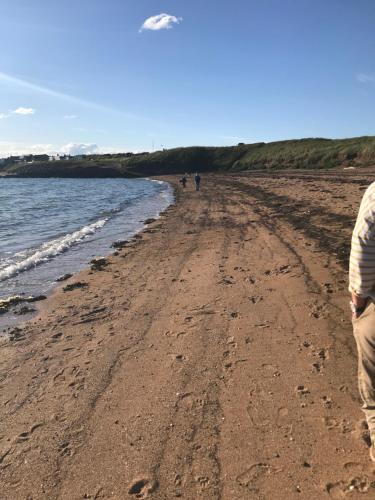 una persona che cammina su una spiaggia vicino all'acqua di West View Cottage in Seaside Village of Allonby Cumbria ad Allonby