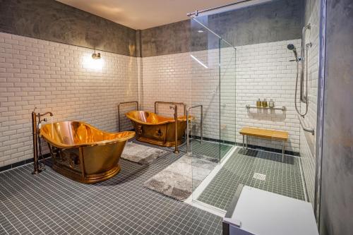 y baño con ducha y 2 bañeras de cobre. en Pivovar Hotel en Waco