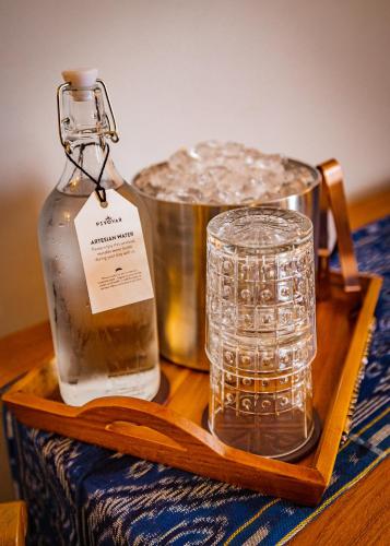 a bottle of water and a glass on a wooden tray at Pivovar Hotel in Waco