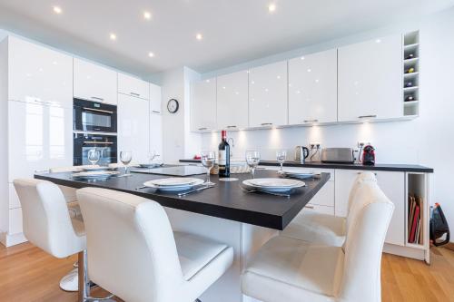 - une cuisine avec une table, des chaises blanches et un comptoir dans l'établissement Sea View Large 2 Bdr Promenade des Anglais, à Nice