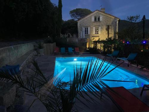 a swimming pool in front of a house at night at Suite Petite -Nice - SPA-JACUZZI - MASSAGE- SAUNA - 4 SAISONS - Piscine Chauffée Toute l'année - POOL VIEW- Heated Pool 800m city centre Nyons in Nyons