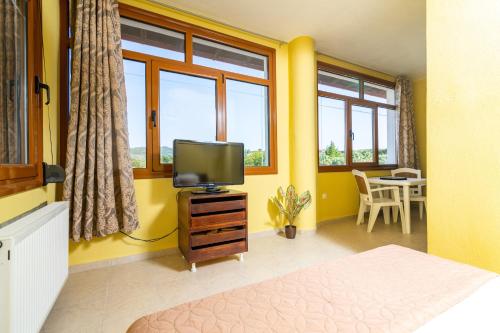 a bedroom with yellow walls and a tv and a table at F & B Summer Collection - Kassandra - Fourka in Skála Foúrkas