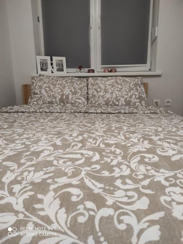 ein Schlafzimmer mit einem Bett mit einer Bettdecke und Kissen in der Unterkunft Apartament Spokojny in Mielno