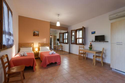 a room with two beds and a table and chairs at Tenuta Li Fani Residence Hotel in Marina di Pescoluse