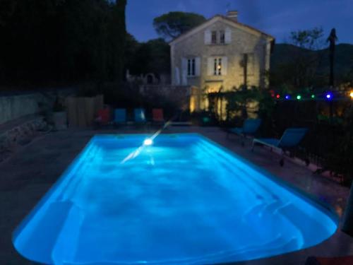 a blue pool with a house in the background at night at La Viste - SPA-JACUZZI - MASSAGE- SAUNA - 4 SAISONS - Piscine Chauffée Toute l'année - Heated POOL - 800m City Centre in Nyons