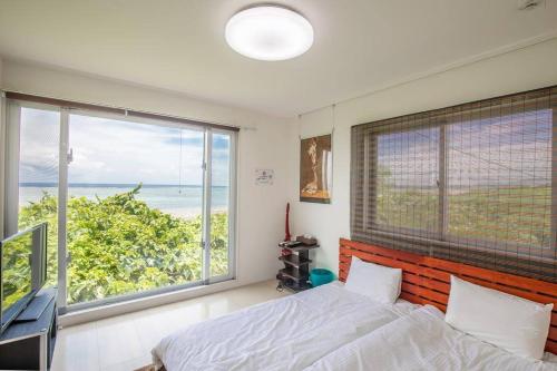 a bedroom with a bed and a large window at "オーシャンビュー ヴィラ南十字星 " Two-Bedroom Villa in Ishigaki Island