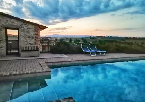 a couple of chairs sitting next to a swimming pool at Borgo Solario in Castiglione del Lago