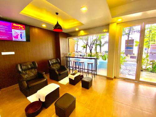 a living room with chairs and a bar with a tv at Beach Breeze and Spa in Hulhumale