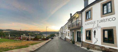 a street in a town with a rainbow in the sky at Huellas Albergue-Turístico in Portomarin