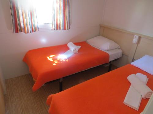 two beds in a small room with orange sheets at Camping Mia Bungalow & Mobile Home in Biograd na Moru