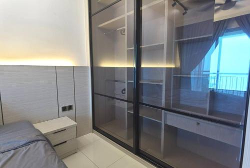 a bedroom with a glass closet with a bed and a window at Teega Suites Puteri Harbour #Seaview Unit in Nusajaya