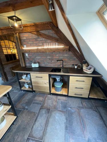 an attic kitchen with a sink and a brick wall at Muggel Apartments in Alpirsbach