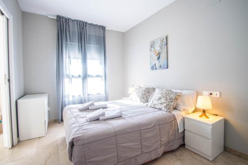 Habitación blanca con cama y ventana en Recogidas Apartment by A3Rentals, en Granada