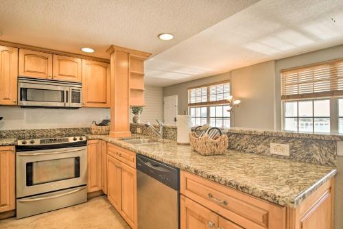 a kitchen with wooden cabinets and granite counter tops at Coastal Clearwater Condo Half Mile to Beach! in Clearwater Beach
