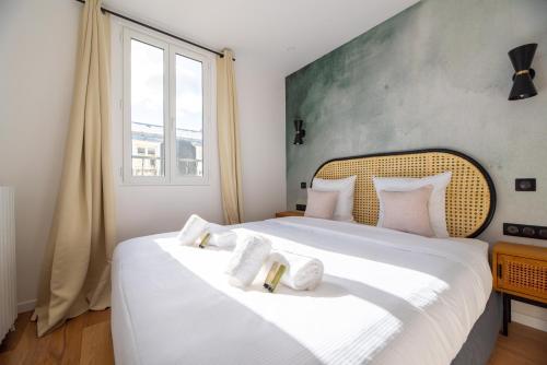 sypialnia z dużym białym łóżkiem z białymi poduszkami w obiekcie Vignature residence w mieście Asnières-sur-Seine